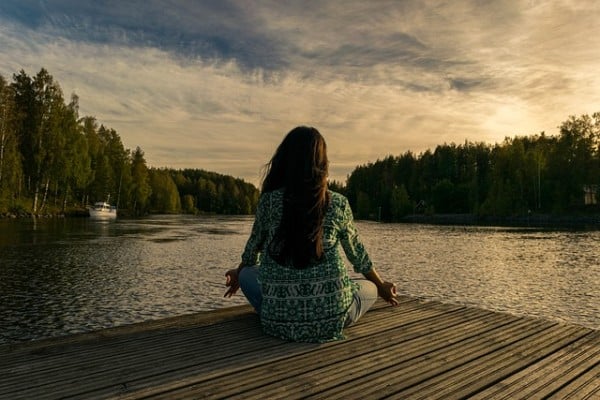 Girl doing yoga beside water